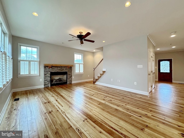 unfurnished living room with stairway, light wood-style flooring, visible vents, and a healthy amount of sunlight