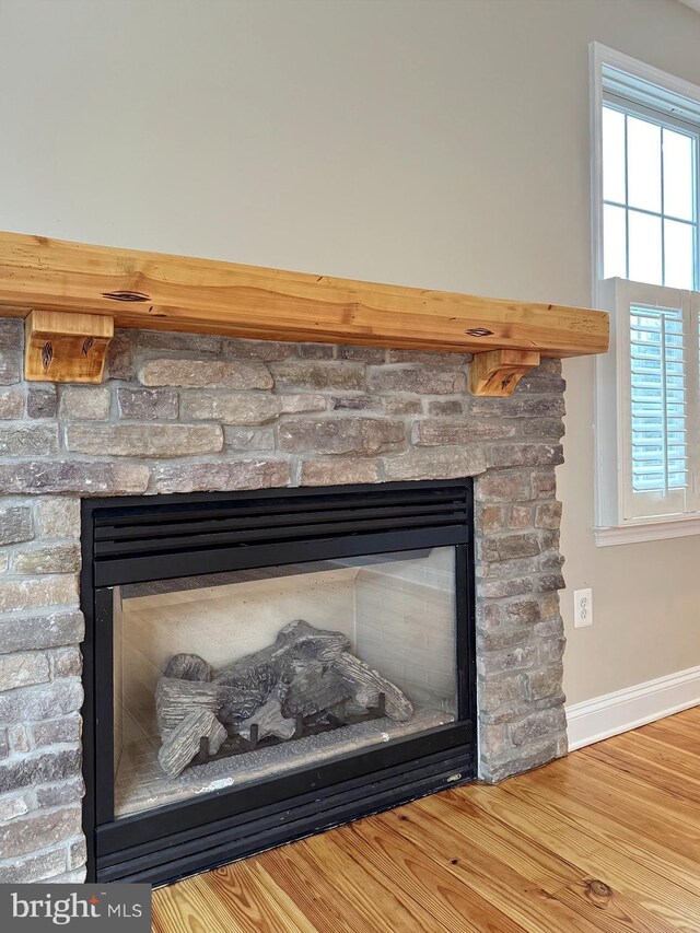 interior details with wood finished floors, a fireplace, and baseboards