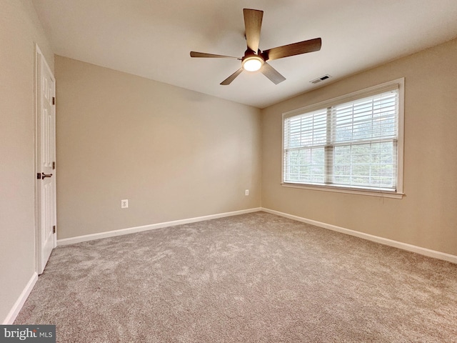 carpeted spare room with visible vents, baseboards, and a ceiling fan