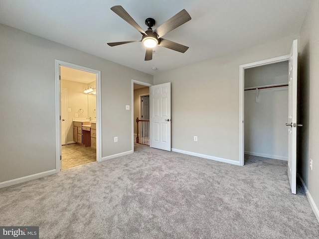 unfurnished bedroom featuring connected bathroom, baseboards, ceiling fan, light carpet, and a closet