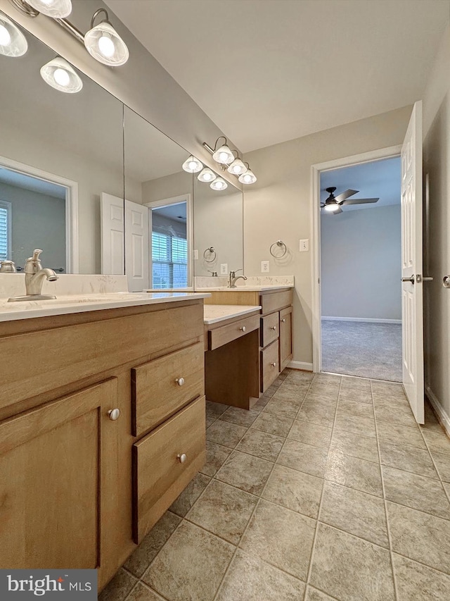 bathroom featuring a ceiling fan, two vanities, baseboards, and a sink