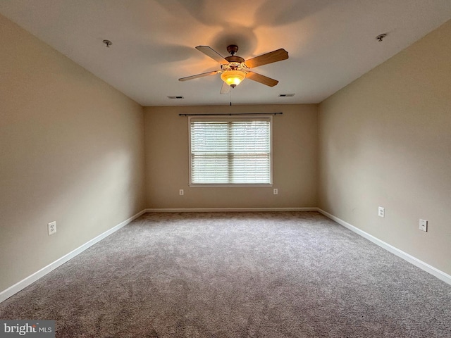 carpeted empty room featuring a ceiling fan, visible vents, and baseboards