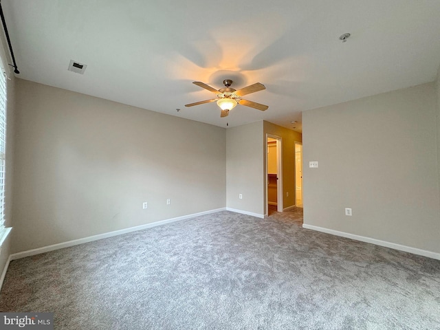 carpeted spare room featuring visible vents, baseboards, and a ceiling fan