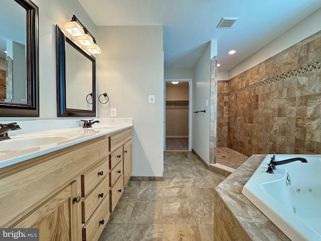 bathroom with visible vents, a walk in closet, a tub with jets, and a sink