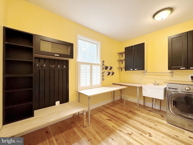 clothes washing area featuring baseboards, washer / dryer, light wood-style flooring, cabinet space, and a sink