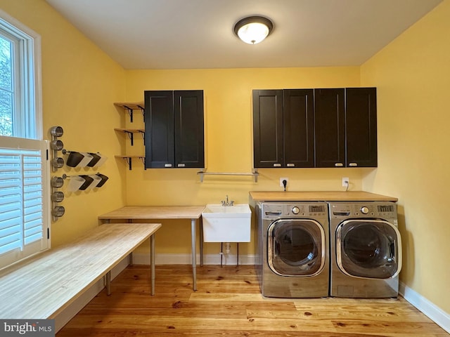 washroom with washer and dryer, cabinet space, light wood-style floors, and baseboards