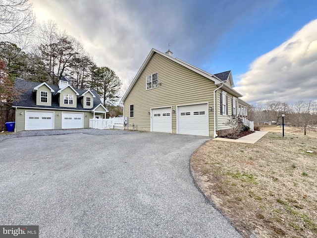 view of side of home featuring aphalt driveway and fence