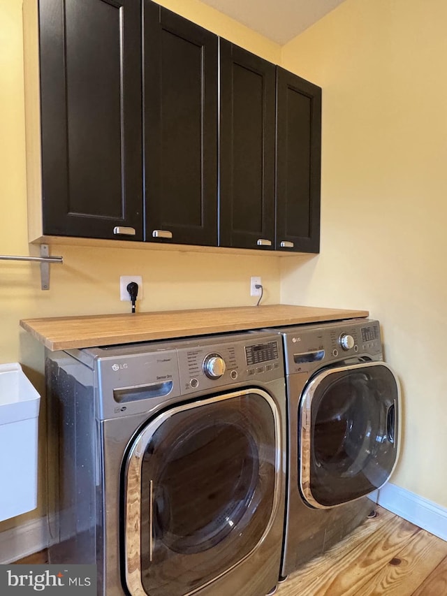 laundry room featuring cabinet space, baseboards, and washer and clothes dryer