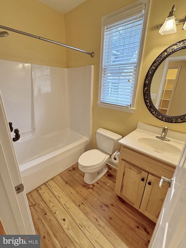 bathroom with toilet, vanity, bathtub / shower combination, and wood finished floors