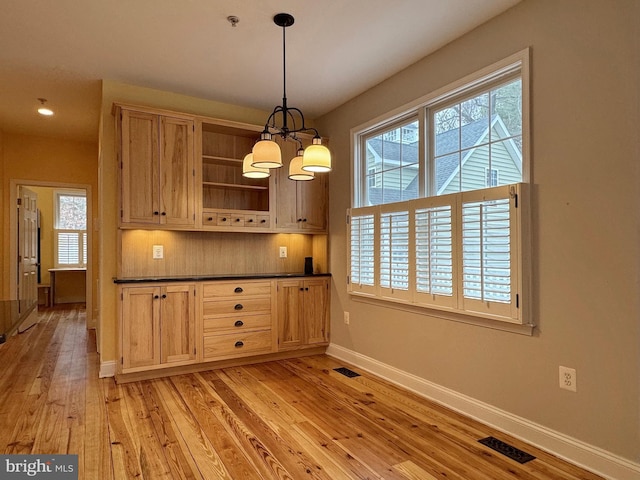 kitchen with dark countertops, light wood-style floors, visible vents, and a wealth of natural light