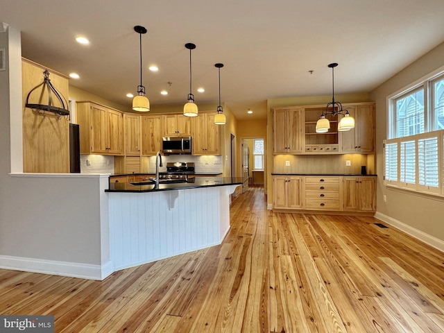 kitchen featuring dark countertops, visible vents, light wood finished floors, a peninsula, and stainless steel microwave