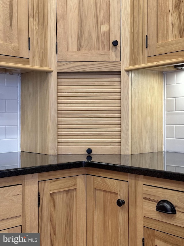 interior details featuring backsplash, dark countertops, and light brown cabinets