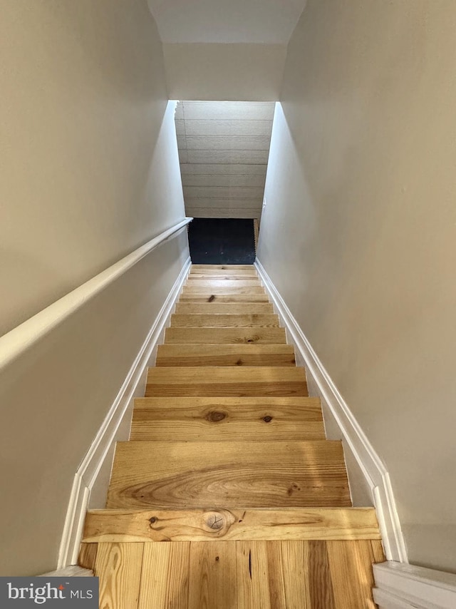 stairway with wood finished floors and baseboards