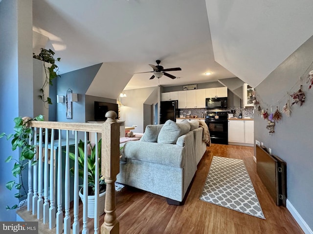 living room with ceiling fan, baseboards, and wood finished floors