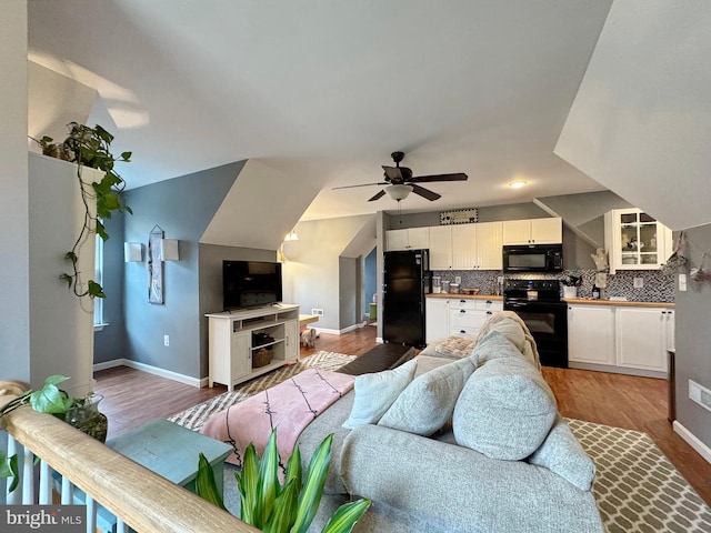 living room with baseboards, a ceiling fan, and light wood finished floors