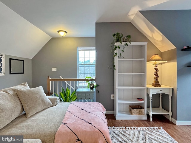 bedroom with baseboards, wood finished floors, and vaulted ceiling