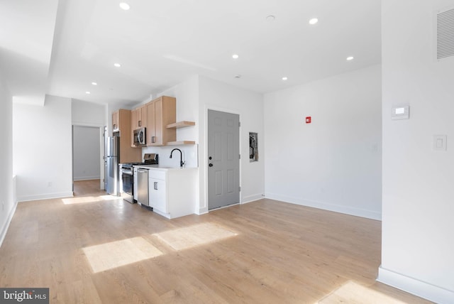 kitchen with stainless steel appliances, light countertops, light brown cabinetry, light wood-type flooring, and open shelves