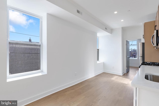 kitchen featuring baseboards, appliances with stainless steel finishes, light countertops, light wood-type flooring, and recessed lighting