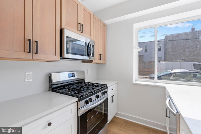 kitchen featuring light countertops, appliances with stainless steel finishes, light brown cabinetry, and light wood-style floors