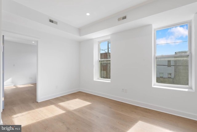 empty room with light wood-style flooring, visible vents, baseboards, and recessed lighting