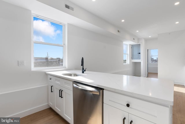 kitchen with visible vents, white cabinetry, a sink, dishwasher, and a peninsula