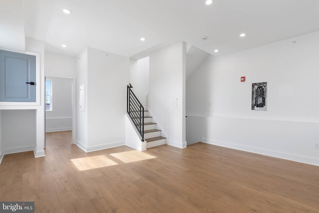 spare room featuring light wood-style flooring, stairs, baseboards, and recessed lighting