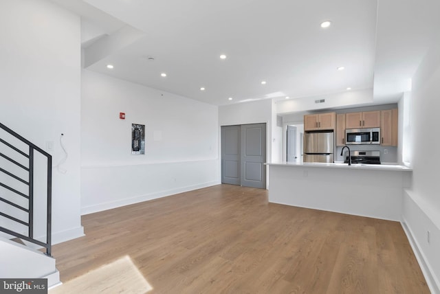 unfurnished living room featuring light wood-type flooring, stairway, baseboards, and recessed lighting