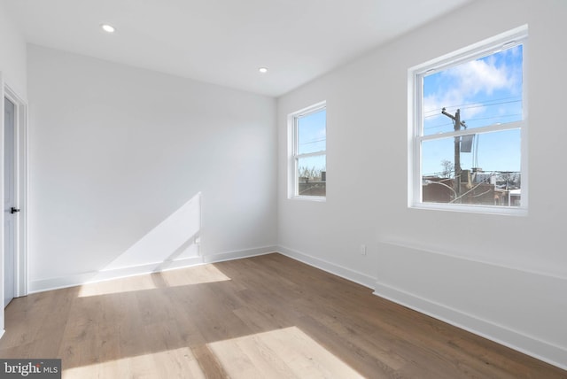 empty room with light wood-type flooring, a healthy amount of sunlight, baseboards, and recessed lighting