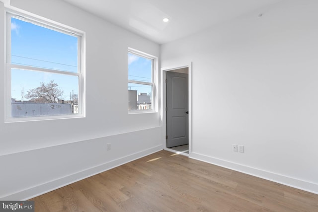 unfurnished room featuring recessed lighting, wood finished floors, and baseboards