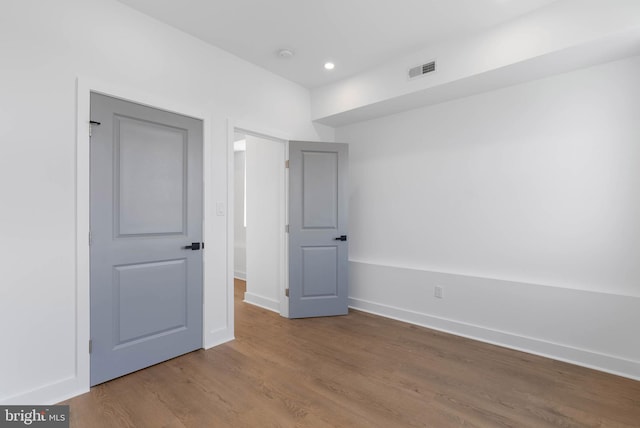 empty room with visible vents, baseboards, wood finished floors, and recessed lighting