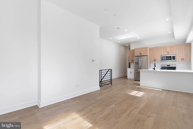 kitchen with light wood-style flooring, stainless steel appliances, light countertops, and light brown cabinetry