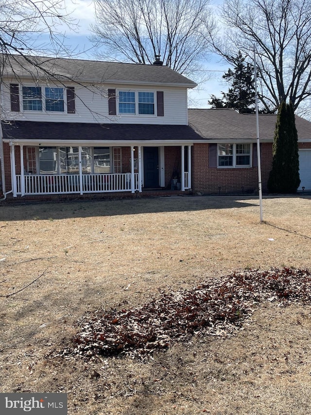 traditional-style home featuring brick siding, covered porch, and a front lawn