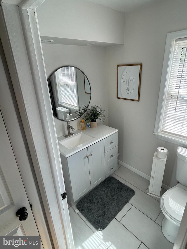 bathroom featuring toilet, tile patterned flooring, vanity, and baseboards