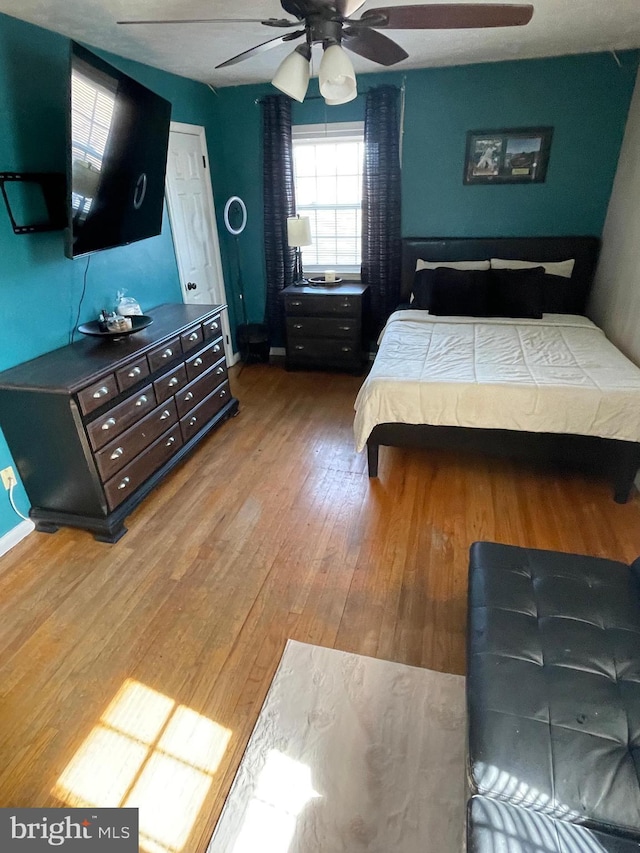 bedroom featuring ceiling fan, baseboards, and wood finished floors