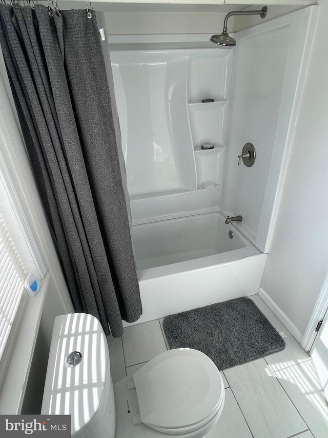 bathroom featuring baseboards, shower / bathtub combination with curtain, and toilet