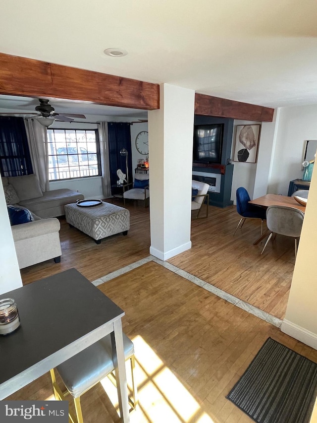 living area featuring ceiling fan, baseboards, and wood finished floors