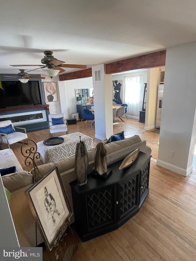 living room with visible vents, ceiling fan, light wood-style flooring, and baseboards