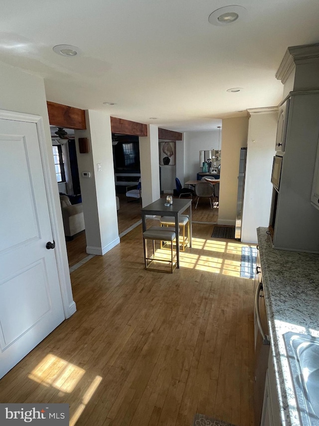 interior space featuring baseboards, dark wood-style floors, light stone counters, open floor plan, and a sink