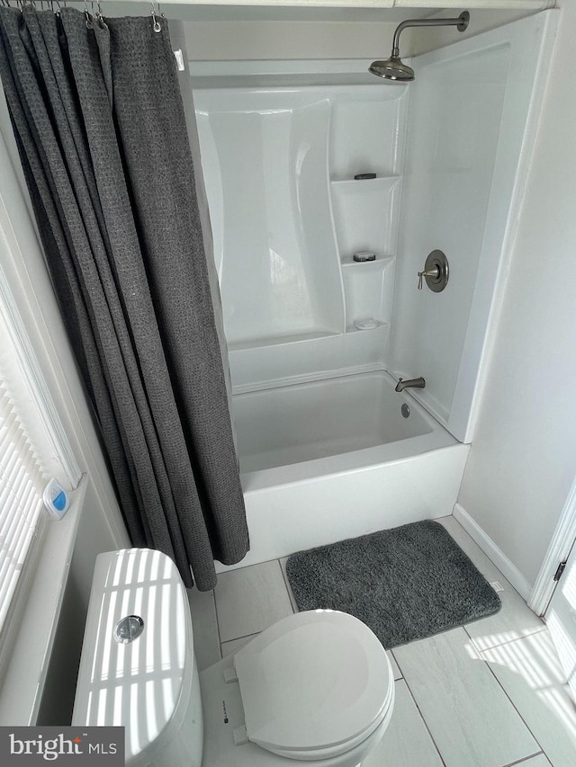 bathroom with shower / bath combination with curtain and toilet