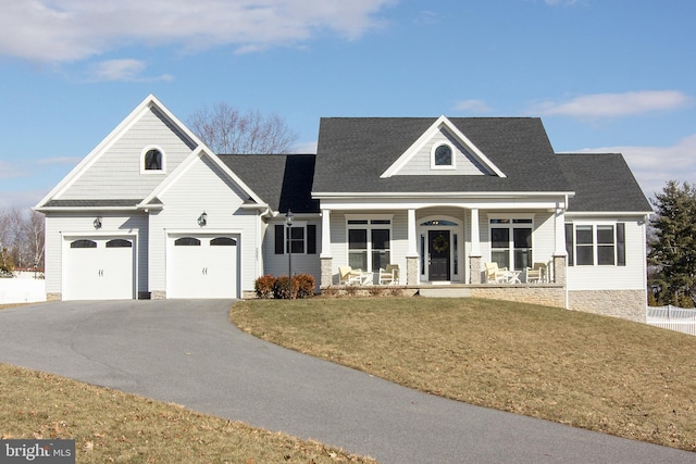 view of front of home with a porch, a front yard, roof with shingles, and driveway