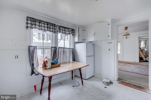 kitchen with light floors, white cabinetry, freestanding refrigerator, and baseboards