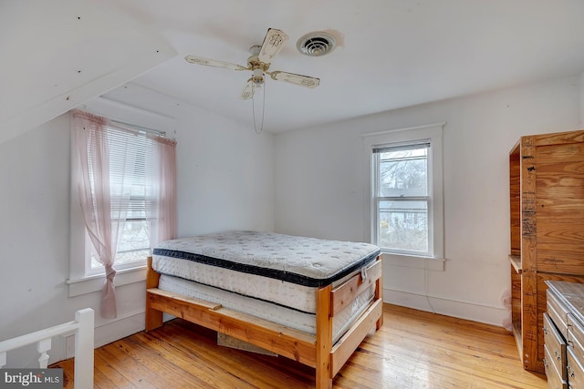 bedroom with light wood-type flooring, visible vents, ceiling fan, and multiple windows