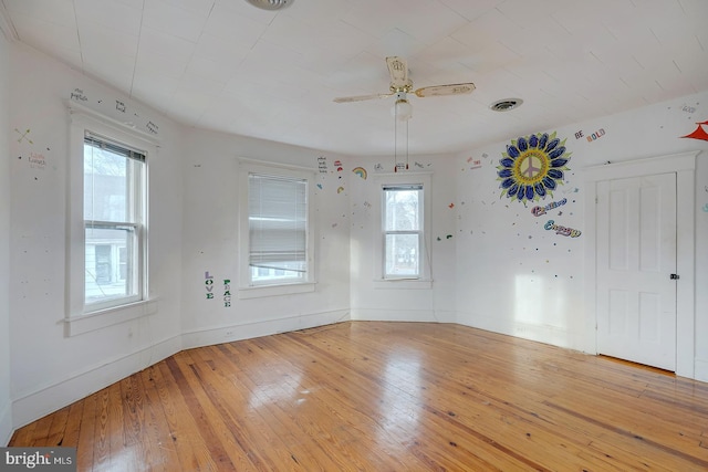 empty room with visible vents, light wood-style flooring, and baseboards