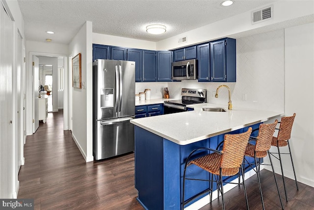 kitchen featuring a breakfast bar area, stainless steel appliances, light countertops, visible vents, and blue cabinets