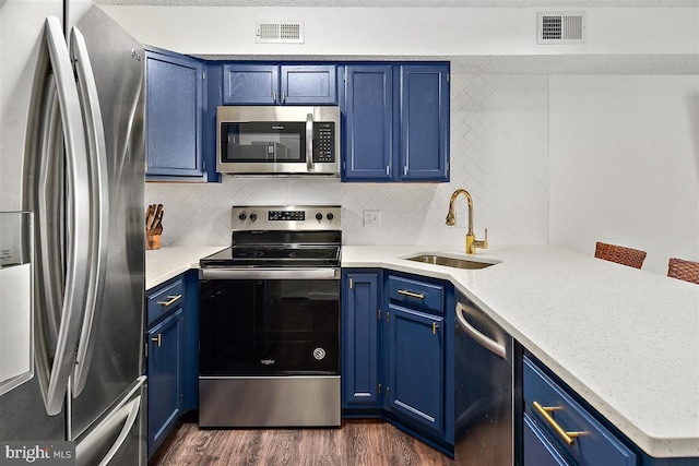 kitchen with appliances with stainless steel finishes, a sink, visible vents, and blue cabinets