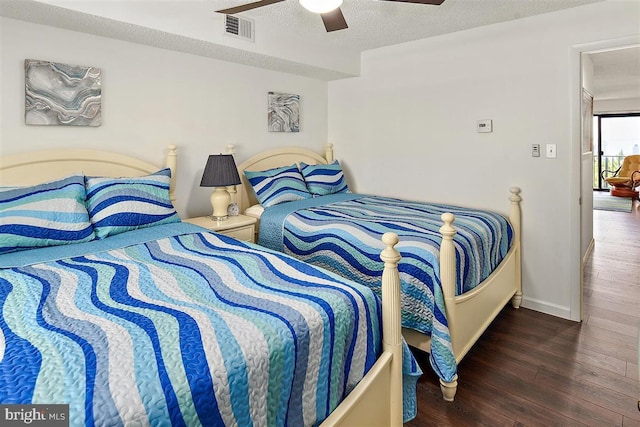 bedroom featuring a textured ceiling, dark wood-type flooring, visible vents, baseboards, and a ceiling fan