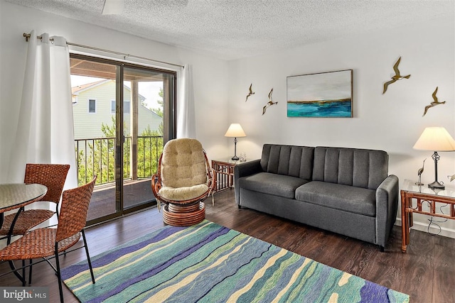 living room with dark wood-type flooring, a textured ceiling, and baseboards