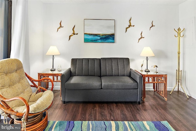 sitting room with dark wood-type flooring and baseboards