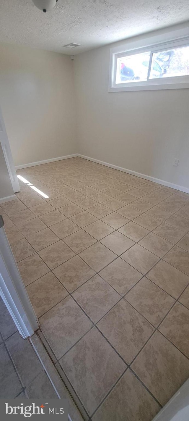 empty room featuring a textured ceiling and baseboards