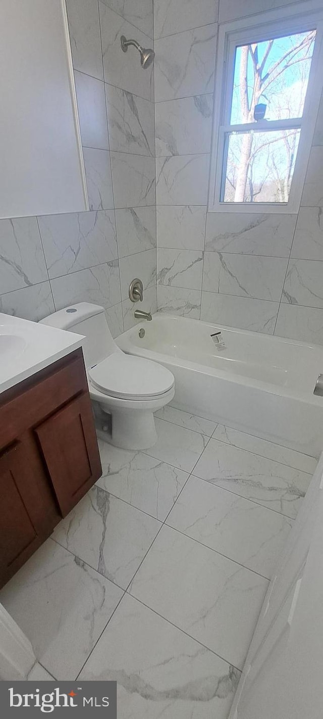 full bathroom featuring toilet, shower / bath combination, vanity, tile walls, and marble finish floor